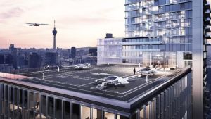 Vliegende taxi's op helikopterplatform van wolkenkrabber, met Lilium logo en stad op achtergrond.