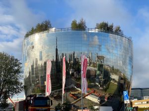 Grote glazen, ronde gebouw met bomen op het dak. Vlaggen met "Het Nieuwe Instituut".