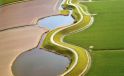 Bochtige waterwegen omgeven door groene en bruine akkers.