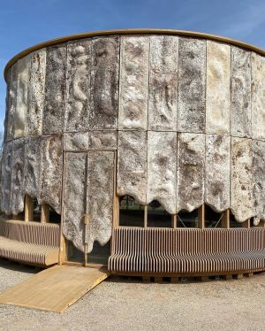 Ronde, stenen structuur met houten zitbanken en toegangshelling.