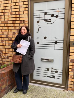Vrouw met papieren voor deur met bladmuziekdecoratie.