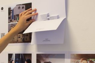 Hand houdt pop-up model van gebouw omhoog, met tekst: 'Superficie Cubierta 8000 m²'.