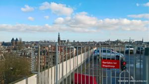 Rode stopbord met stopstreep, verkeerslicht en auto's op parkeerplaats, met stadsuitkijk.