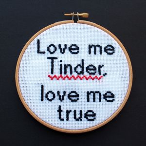 Borduurwerk met tekst "Love me Tinder, love me true" met rode zigzaglijn.
