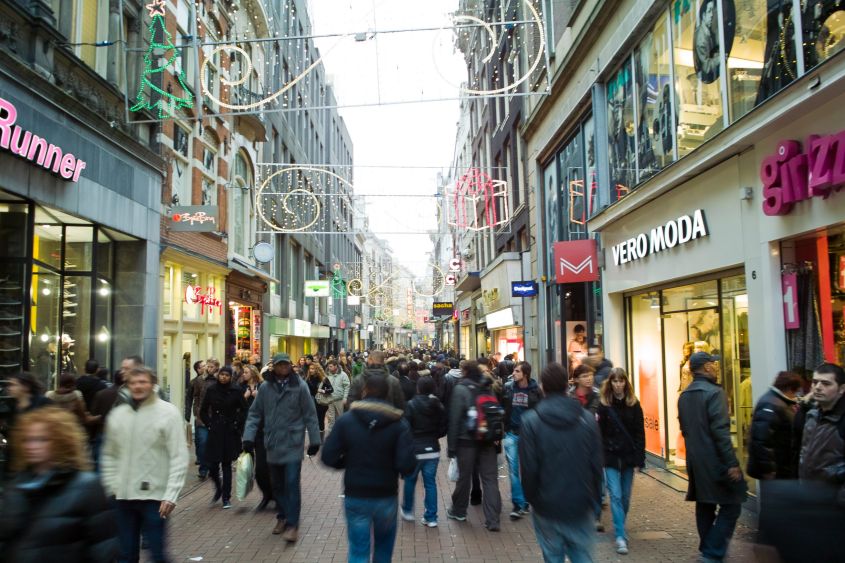 Drukke winkelstraat met mensen, kerstversiering, 'Runner' en 'VERO MODA' tekst.