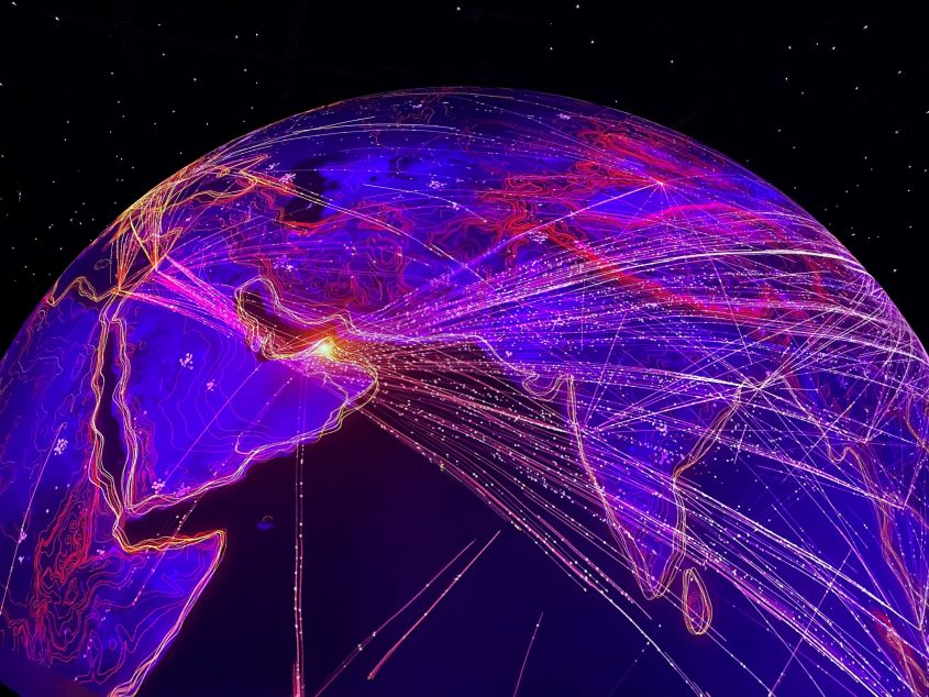 Glooiende blauwe planeet met paarse, oranje en witte lichtlijnen die de verbindingen weergeven.