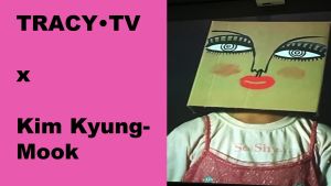 Vak met getekend gezicht op hoofd, tekst TRACY•TV x Kim Kyung-Mook, shirt "So Shy"