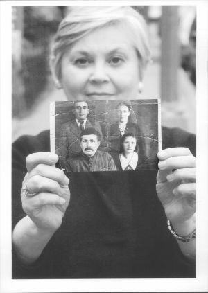 Vrouw houdt oude foto vast met vier personen, een ring op haar hand.