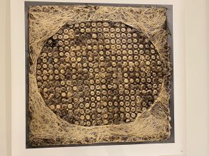 Kunstwerk met een ovaal patroon van opgerolde vezels, omringd door wortelachtige structuren.