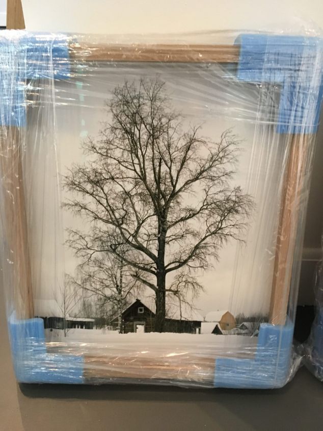 Boom met kale takken in besneeuwd landschap met houten huizen.