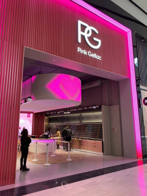 Roze boetiek Pink Gellac met een PG logo. Mensen winkelen bij toonbanken met nail polish.
