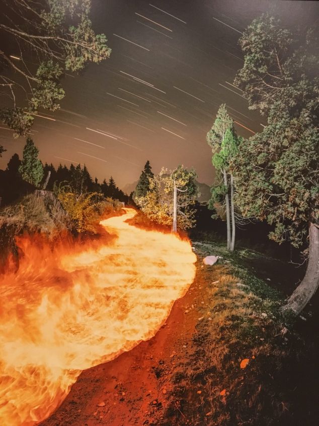 Een pad door vuur onder een sterrenhemel met bomen