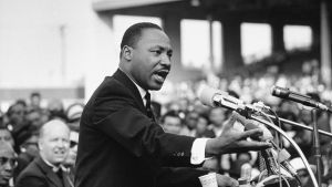 Martin Luther King Jr. spreekt in microfoon voor publiek tijdens demonstratie.