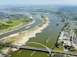 Luchtfoto van de Maas met bruggen en schepen, strandingen en bebouwing aan de oevers.