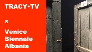 TRACY•TV x Venice Biennale Albania naast openstaande groene deuren met nummer 24