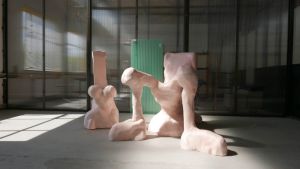 Lichtroze sculpturen in een atelier met gefilterd zonlicht op de vloer.