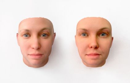 Twee levensechte, 3D-geprinte, kale gezichten met blauwe ogen en roze huid, naast elkaar op een witte achtergrond.