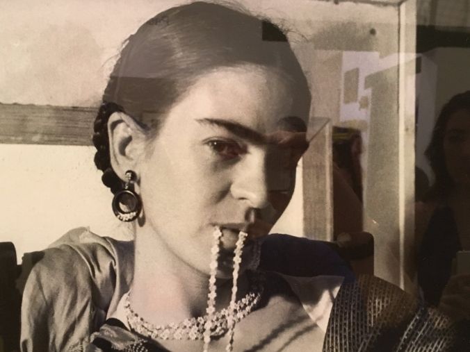 Frida Kahlo met kraaltjes in haar mond, zittend in een studio.