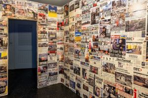 Muur beplakt met krantenkoppen en foto's over de oorlog in Oekraïne, met de tekst 'WRATH OF PUTIN'.