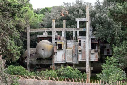 Betonnen constructie met ronde vormen, ramen en vegetatie, die een uniek architectonisch gebouw toont.