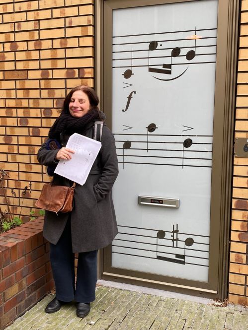 Vrouw met papieren voor deur met bladmuziekdecoratie.
